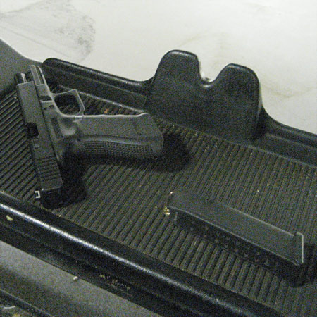 A 9mm Glock 17 pistol laying on a tray beside its magazine which has been removed